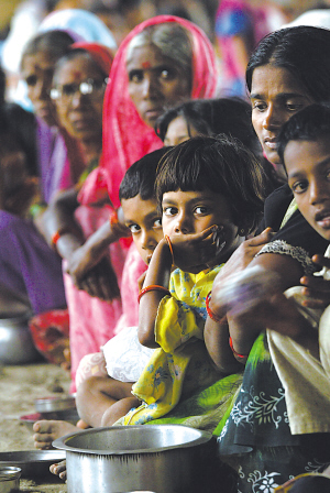 8月8日,印度西部遭受水灾的难民在等待分发食物和水.
