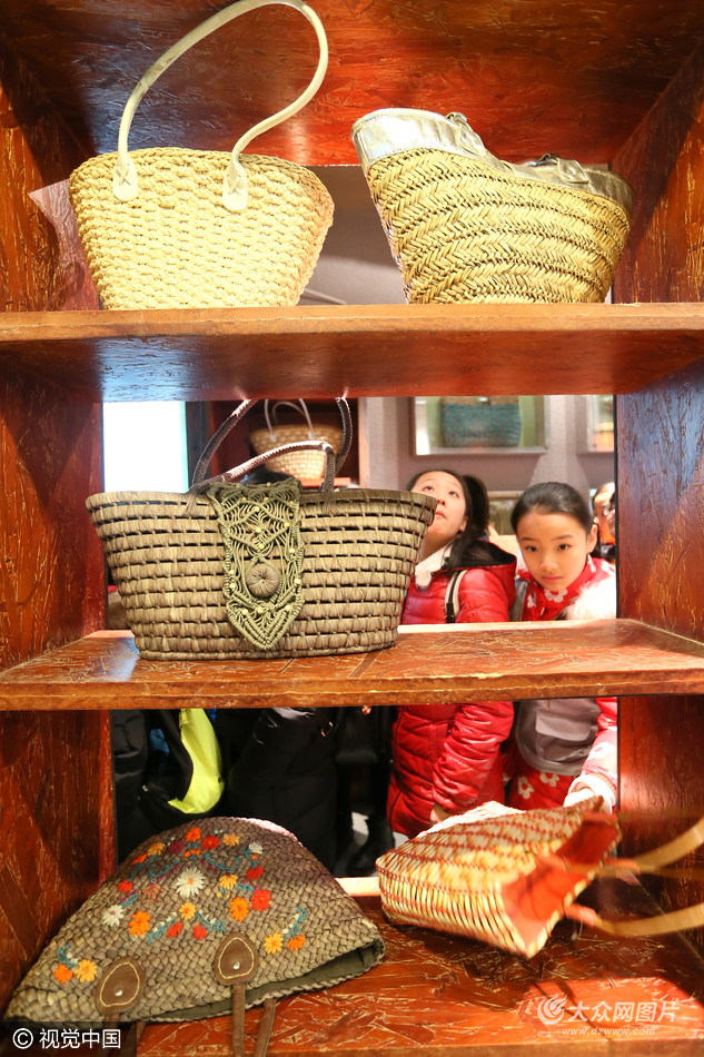 小学生在山东即墨市非物质文化遗产博览园观赏草编制品