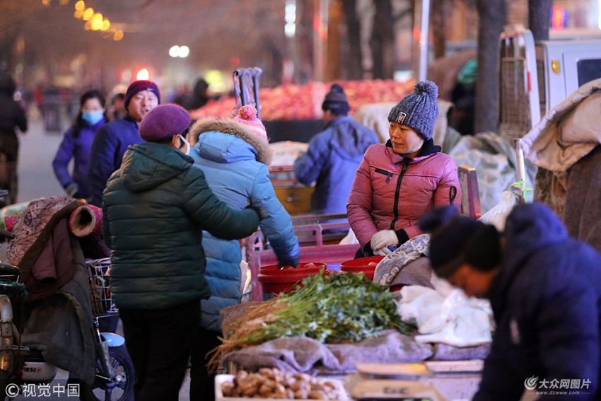 2017年12月14日,山东省潍坊市,早市的商贩们正在马路一侧忙碌的经营着
