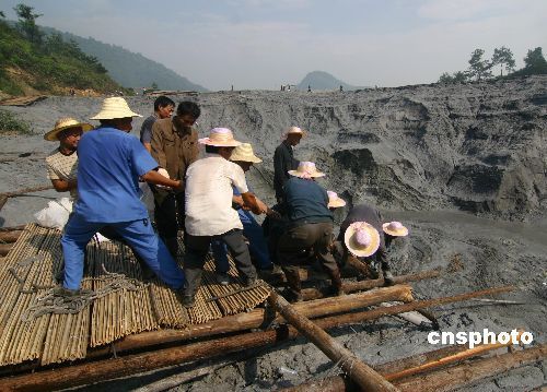 7月28日,许多工人在冷水江市中泰矿业公司发生尾砂泄漏的尾砂坝进行